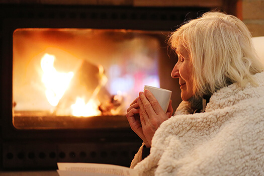 blog Cozy-Senior-Woman-Drinking-Tea-By-Fireplace